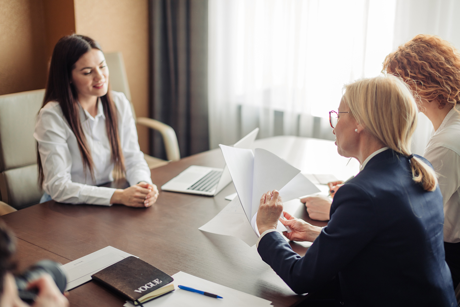 Woman job applicant having an interview with two female corporate experts at office of big company. Two young beautiful women, conducting a job interview reading the female candidate s CV.