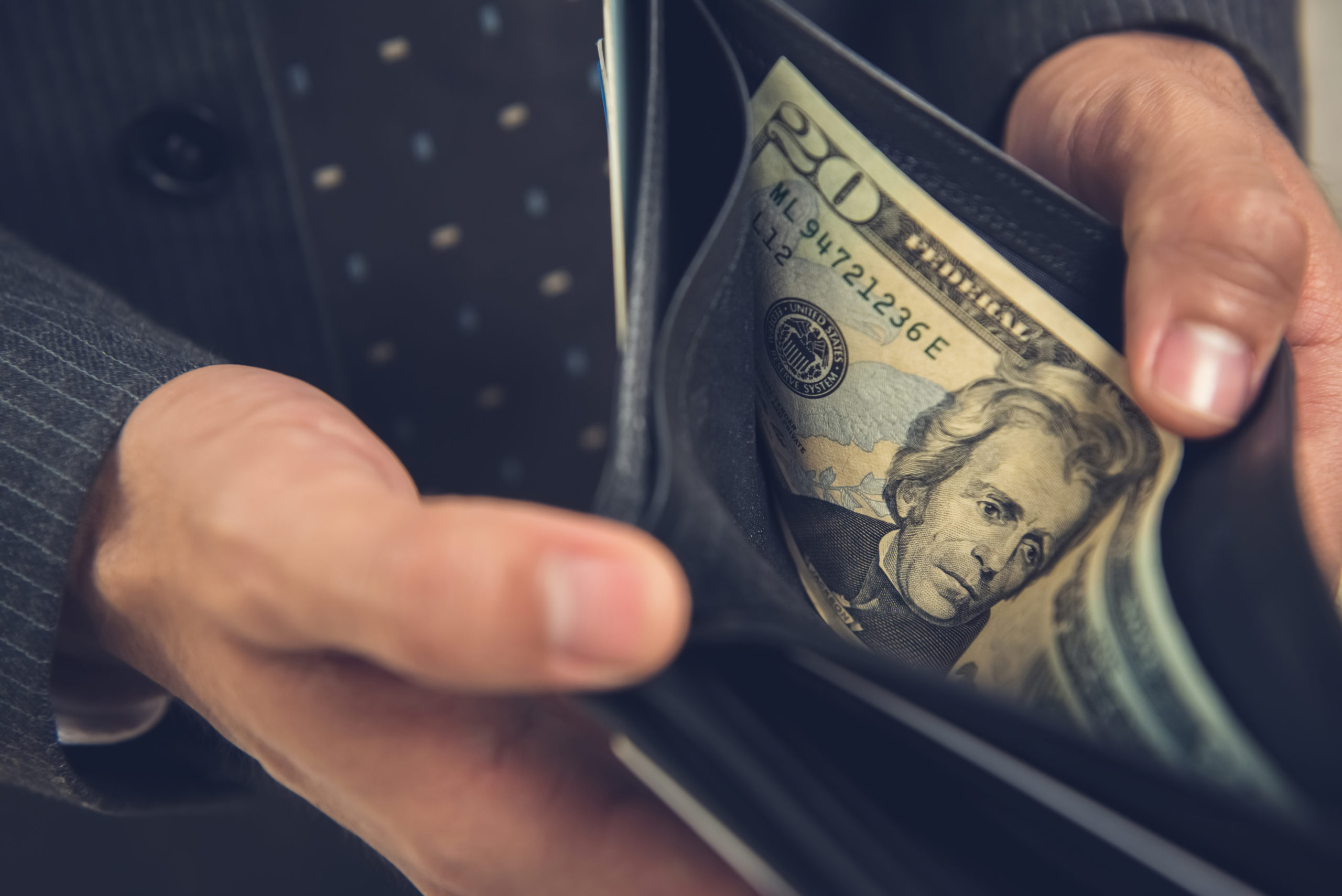 A man opening wallet showing some money, 20 US dollar bill left