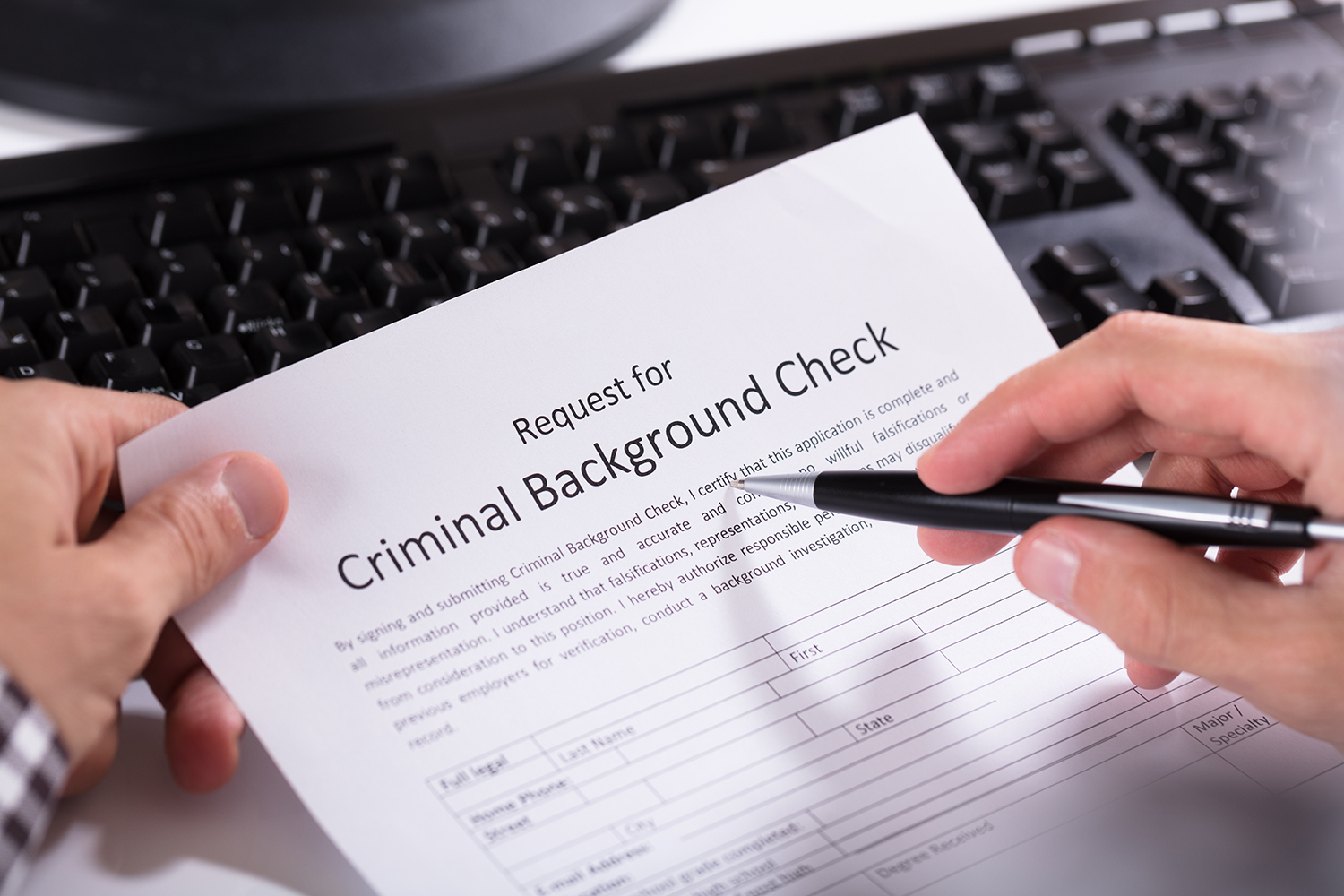 Close-up Of Person Hand Filling Criminal Background Check Application Form